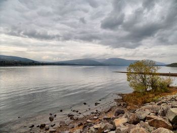 Scenic view of lake and mountains against cloudy sky