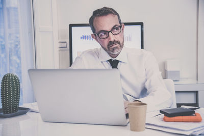 Business man working with laptop sitting at desk. male works at computer online with remote office