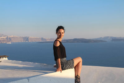 Portrait of young woman sitting on boat at sea against sky