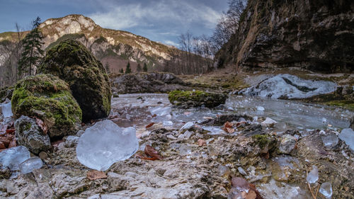 Stream flowing through rocks against sky