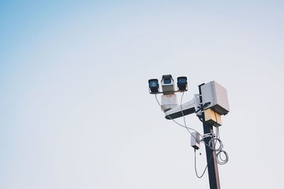 Low angle view of security camera on street light against clear sky