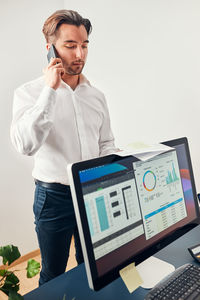 Young man using laptop while standing against white background