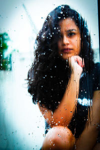 Portrait of woman in wet glass window