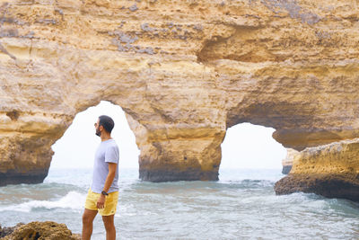 Full length of man standing on rock at beach