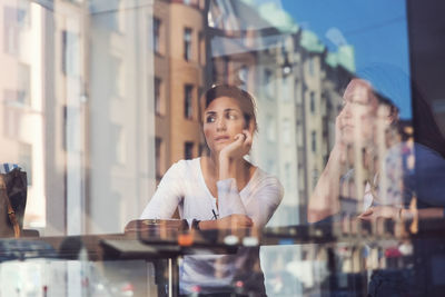 Thoughtful women seen through glass window at cafe