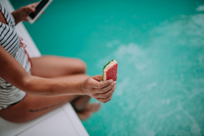 Midsection of woman holding ice cream against sea