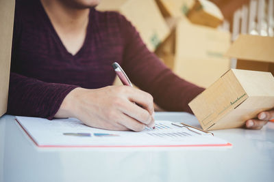 Midsection of woman reading book on table