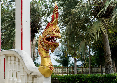 Statue of buddha against trees and building