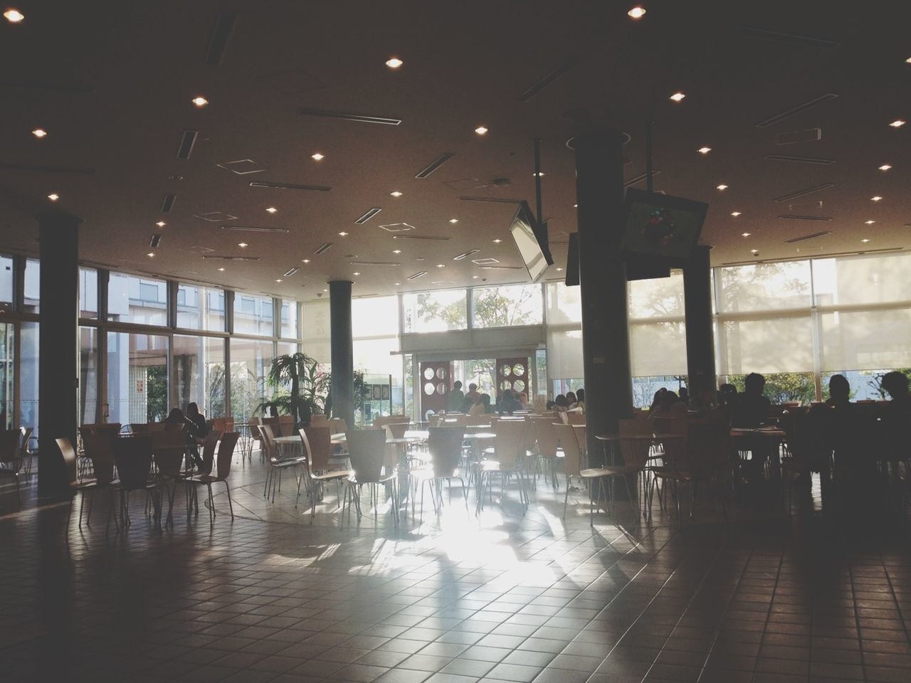indoors, illuminated, built structure, architecture, chair, table, restaurant, reflection, flooring, glass - material, lighting equipment, window, night, empty, incidental people, silhouette, architectural column, ceiling, sunlight