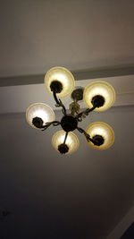 Low angle view of illuminated light bulb hanging on ceiling
