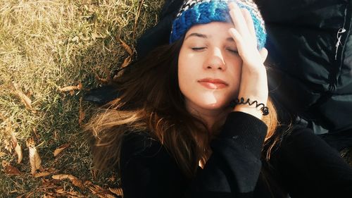 High angle view of woman shielding eyes while lying on land
