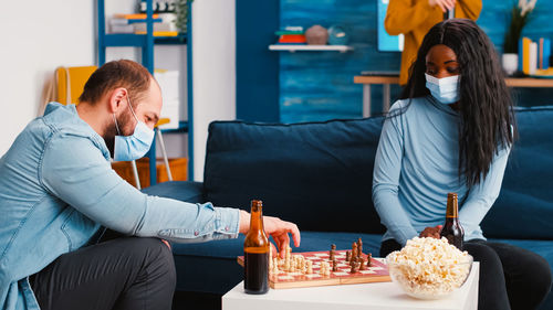 Man and woman wearing mask playing chess