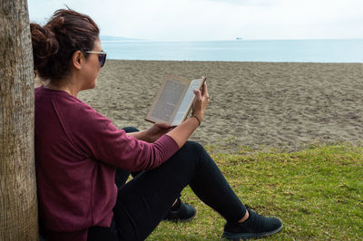 Side view of woman sitting on beach