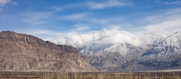 Scenic view of snowcapped mountains against cloudy sky