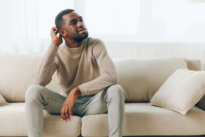 Portrait of young man sitting on sofa at home