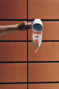 Close-up of hand holding drink against wall