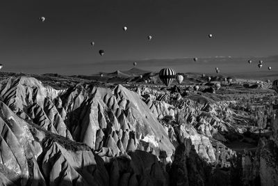 Idyllic shot of hot air balloons flying over dramatic landscape at cappadocia against sky
