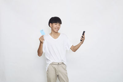 Portrait of smiling young man standing against white background