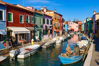 Boats moored in canal amidst buildings in city