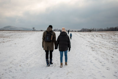 Rear view of friends standing on snow covered land