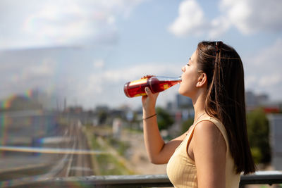 Woman drinking while standing in city