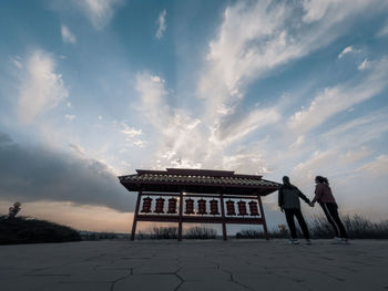 People on building terrace against sky during sunset