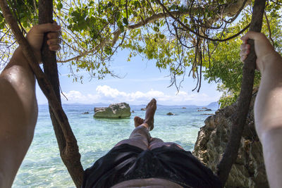 Low section of man on swing at shore of beach