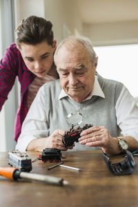 Portrait of senior man and grandson with toy train at home