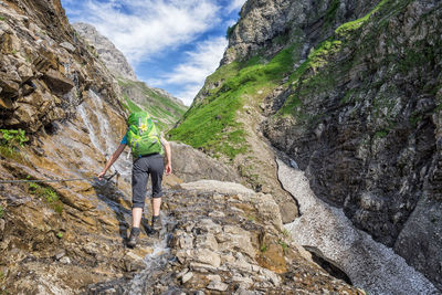 Rear view of woman standing on rock against sky