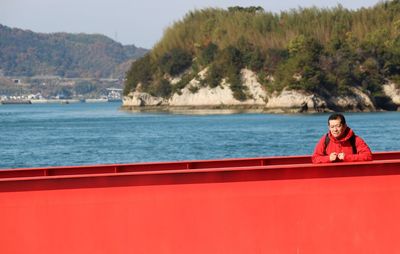 Portrait of girl on red boat against trees
