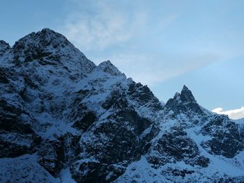 Low angle view of snowcapped mountains against sky