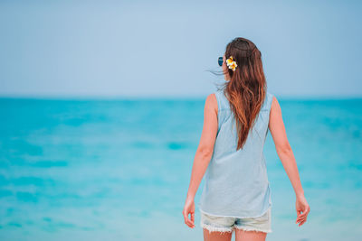 Woman standing in sea against sky