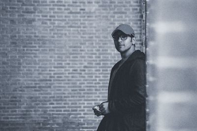 Portrait of young man looking away against wall