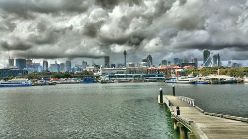 Boats at harbor against cloudy sky