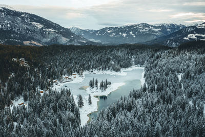 Scenic view of lake amidst forest and snowcapped mountains against sky