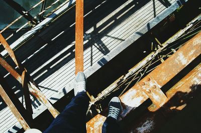 Low section of person standing on bridge during sunny day