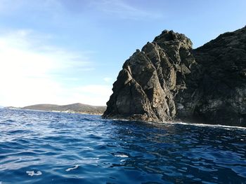 Rock formation in sea against sky