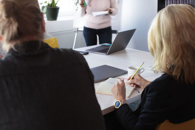 Woman taking notes during business presentation