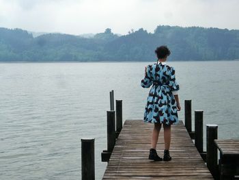 Man standing on pier at lake
