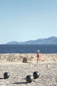 Woman walking at beach against clear sky