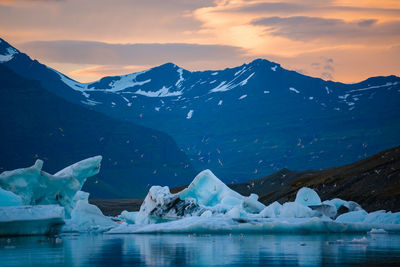 Scenic view of icebergs on lake against sky during sunset