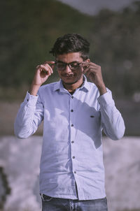 Young man wearing sunglasses standing outdoors.