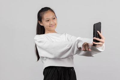 Portrait of smiling young man using smart phone against white background