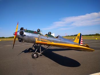 Airplane on airport runway against sky on sunny day