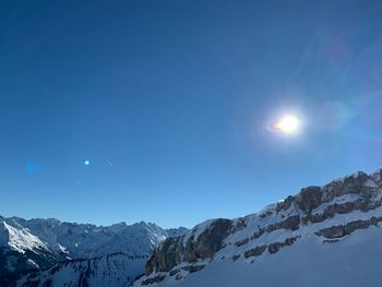 Scenic view of snowcapped mountains against blue sky