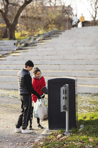 Male and female volunteers throwing plastic in garbage can