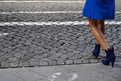 Low section of woman standing on cobblestone