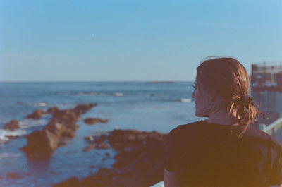 Side view of woman looking at sea against clear sky