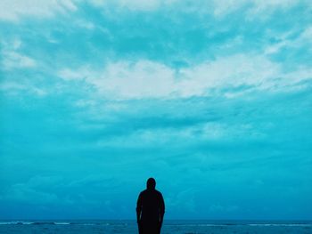 Rear view of silhouette man standing in sea against sky