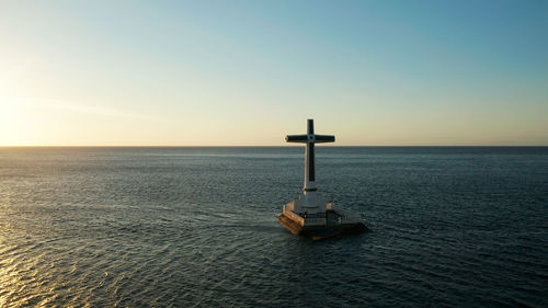 Catholic cross in sunken cemetery in the sea at sunset, aerial drone. 